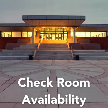 It shows the entrance of University Centre, time of the day the picture was taken is evening sunset, and the entrance is lit up with yellow lights.